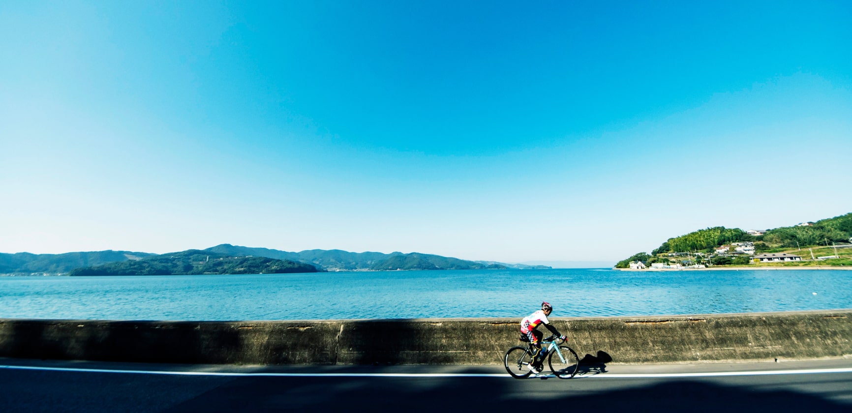 大村湾をのぞみサイクリングをする男性の写真